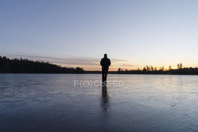 Mann läuft bei Sonnenuntergang auf zugefrorenem See — Stockfoto