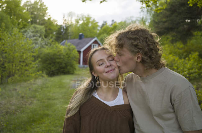 Молодий чоловік цілує жінку щокою — стокове фото