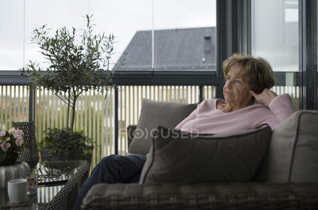 Femme âgée assise sur le canapé — Photo de stock