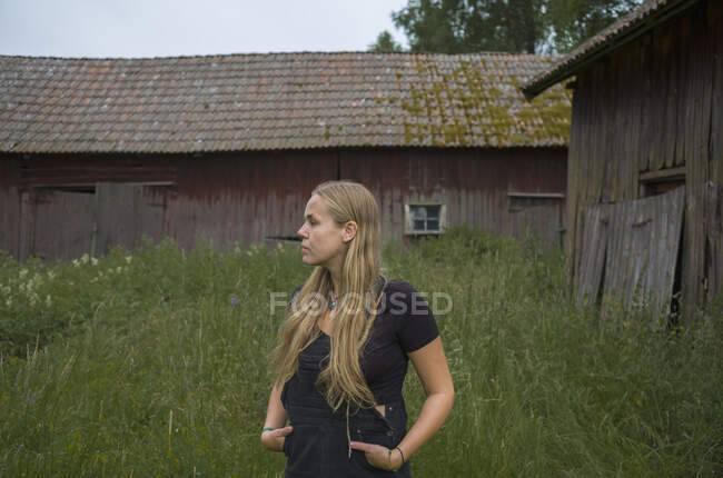 Teenagermädchen steht im Gras neben Scheune — Stockfoto