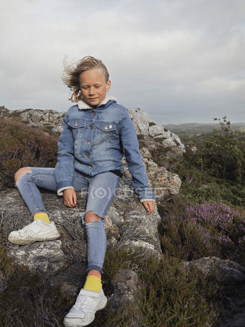 Дівчина в джинсовій куртці сидить на скелі — стокове фото