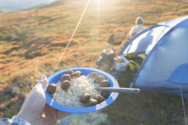 Mano dell'uomo in possesso di piatto di patate e pasta durante il campeggio — Foto stock