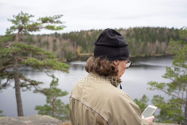 Woman text messaging by river — Stock Photo