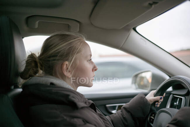 Teenage girl with blonde hair driving car — Stock Photo