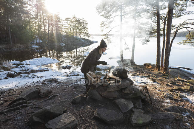 Жінка стоїть біля багаття біля озера — стокове фото