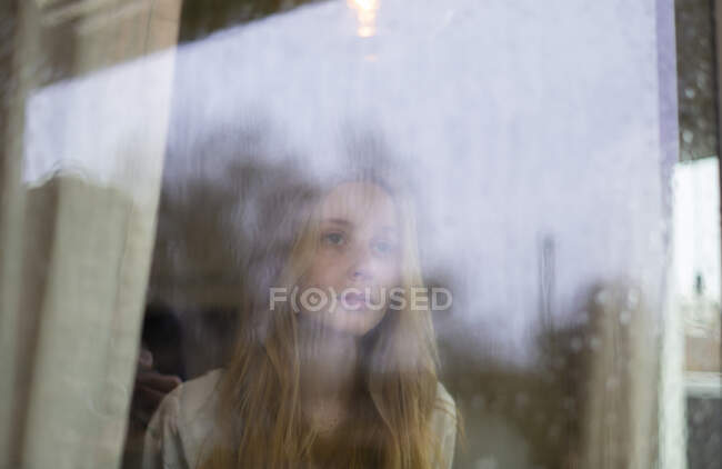 Adolescent fille debout dans fenêtre — Photo de stock