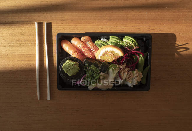 Sushi y palillos sobre mesa de madera - foto de stock