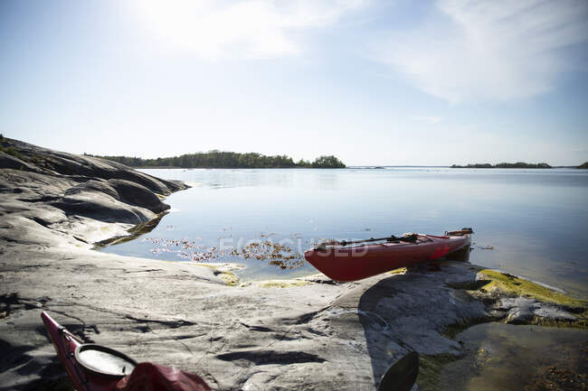 Red kayak on rock by sea — Stock Photo