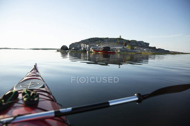 Kayak rojo y hombre acampando en rocas costeras - foto de stock