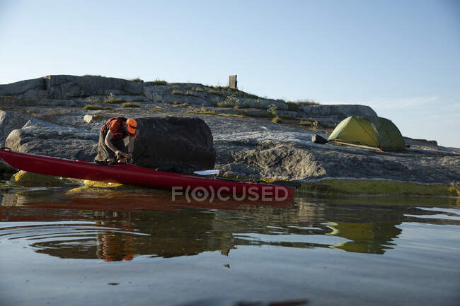 Man with kayak camping on coastal rocks — Stock Photo