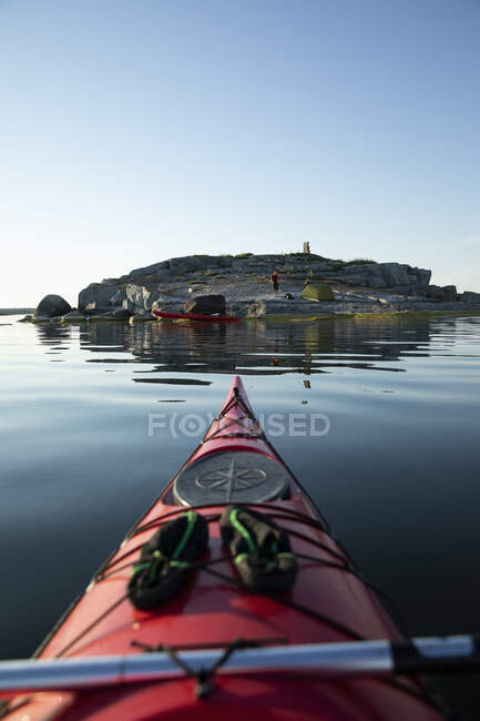 Kayak rosso e uomo campeggio sulle rocce costiere — Foto stock
