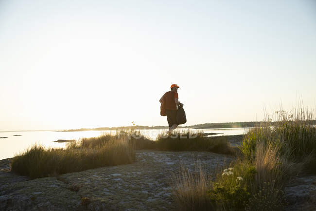 Человек, идущий по берегу на закате — стоковое фото