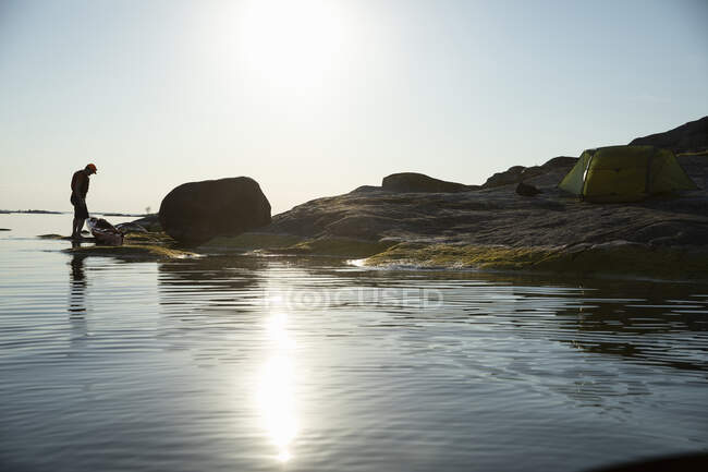 Man camping on coastal rocks — Stock Photo