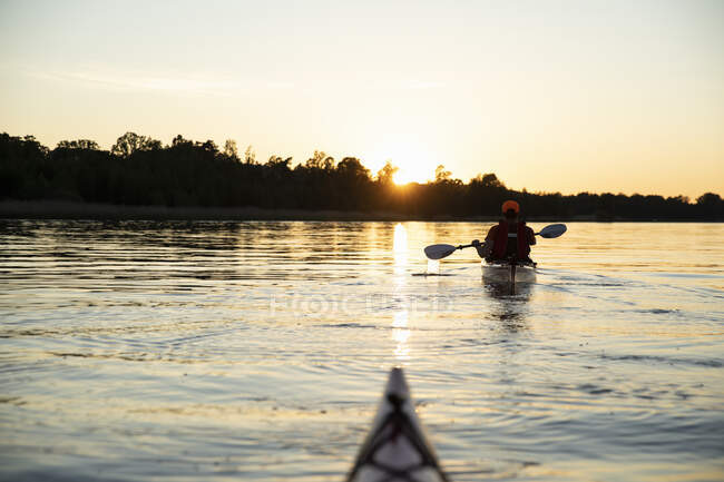 Kayaker en el mar al atardecer - foto de stock