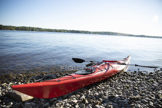 Red kayak on stones by sea — Stock Photo