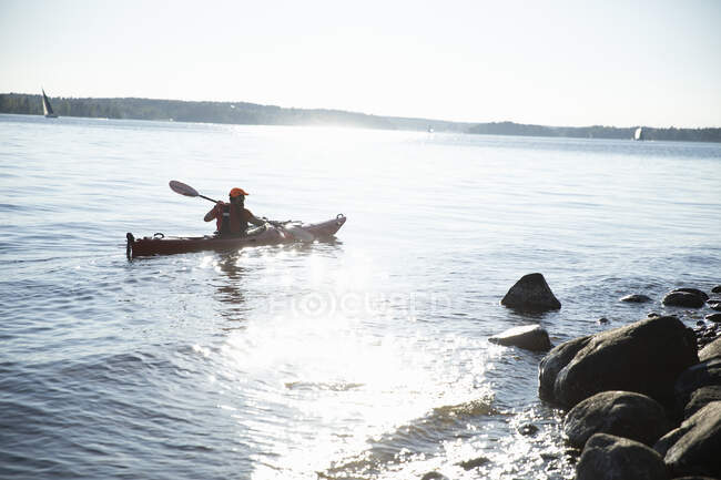 Mann in Schwimmweste paddelt auf See — Stockfoto