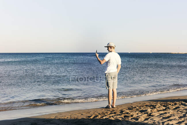 Niño tomando fotografías en la playa - foto de stock