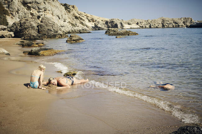 Familia tomando el sol y relajándose en la playa - foto de stock