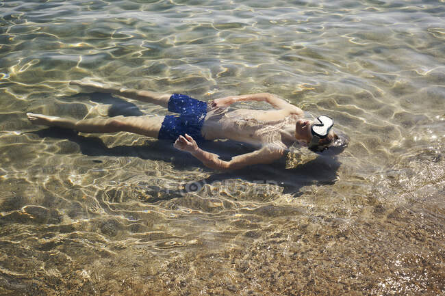 Garçon avec masque de plongée nageant en mer — Photo de stock
