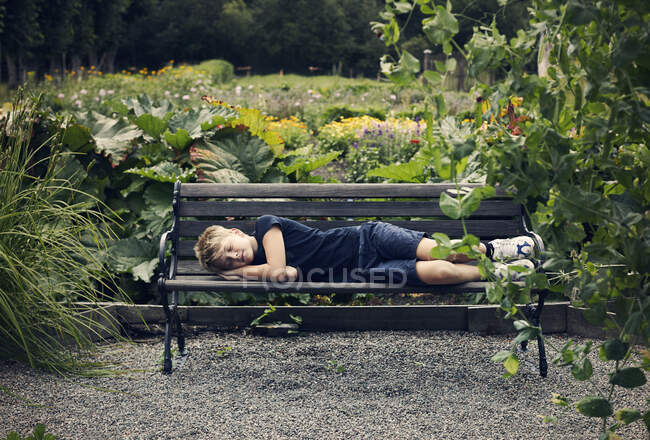 Garçon dormir sur le banc dans le parc — Photo de stock