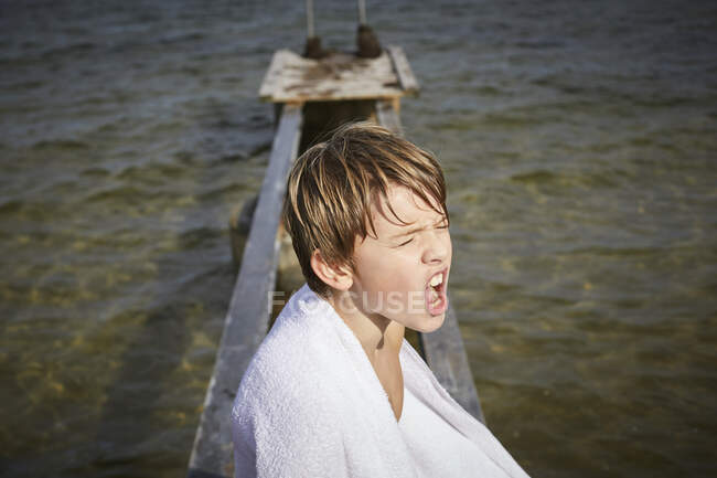 Ragazzo avvolto in asciugamano sul molo — Foto stock