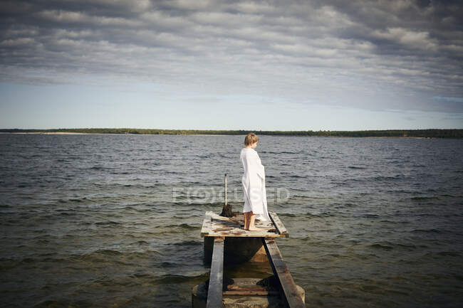 Boy wrapped in towel on jetty — Stock Photo