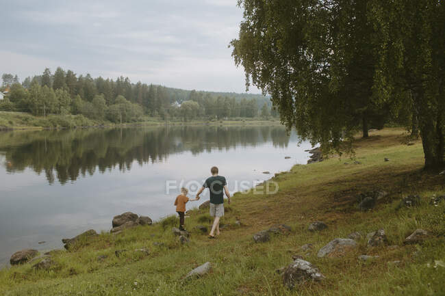 Padre e hija de senderismo por el lago - foto de stock