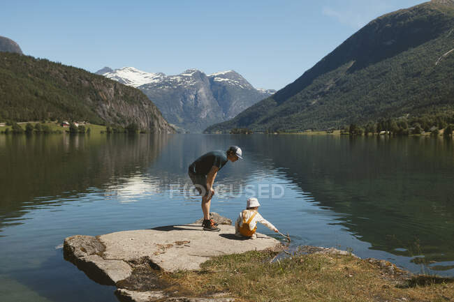 Pai e filha em pé na rocha junto ao lago — Fotografia de Stock