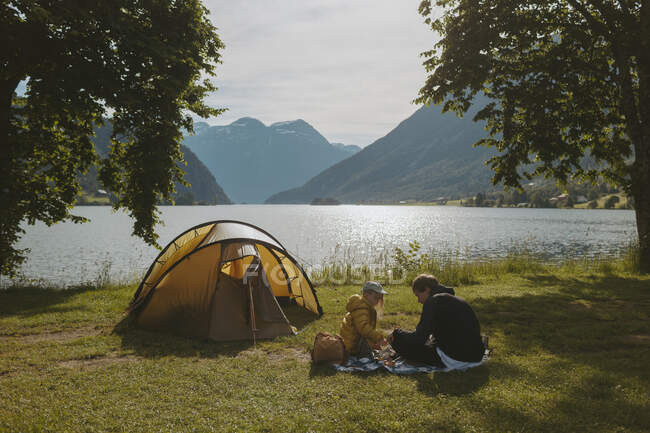Father and daughter camping by lake — Stock Photo