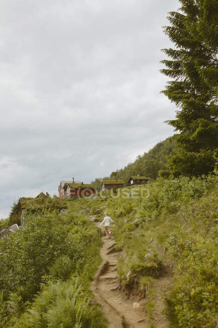 Girl hiking on trail to cabin — Stock Photo