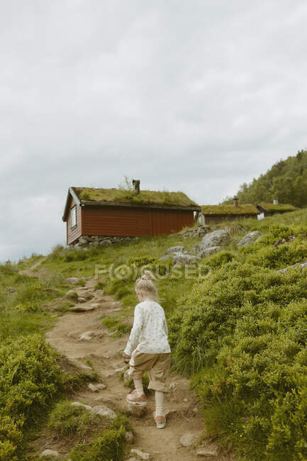 Girl hiking on trail to cabin — Stock Photo
