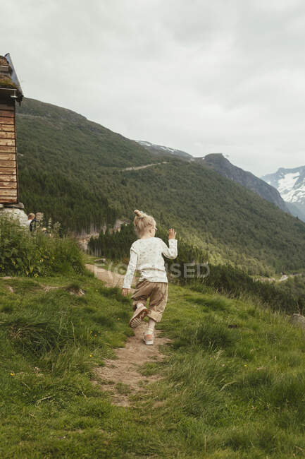 Girl hiking on trail by cabin — Stock Photo