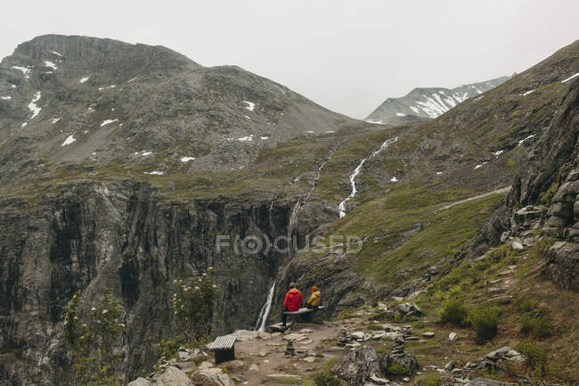 Padre e hija sentados en el banco en la montaña - foto de stock