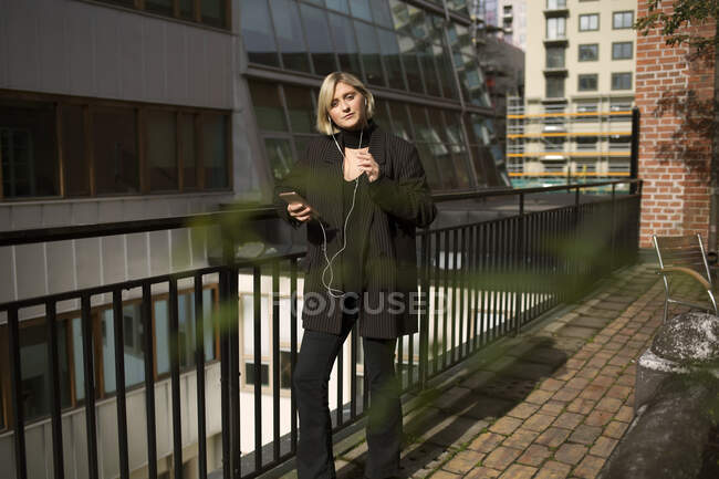 Jeune femme écoutant de la musique sur le balcon — Photo de stock
