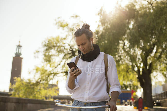 Man with bicycle using smartphone — Stock Photo