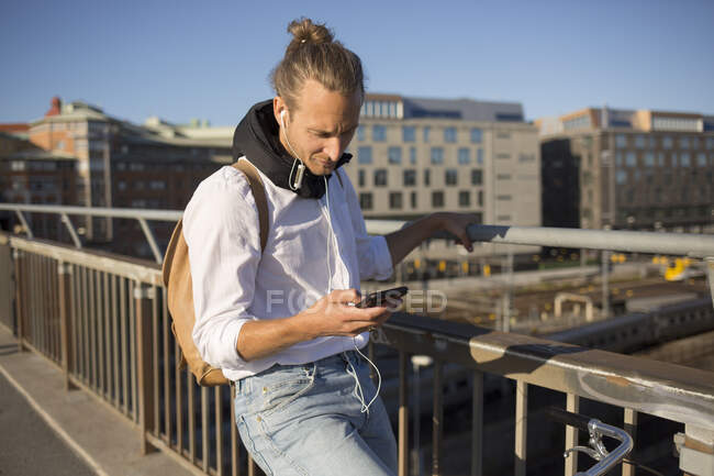 Hombre usando smartphone en puente - foto de stock