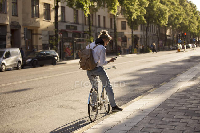 Hombre usando smartphone en bicicleta - foto de stock