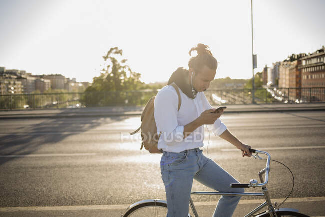 Hombre con bicicleta usando smartphone - foto de stock