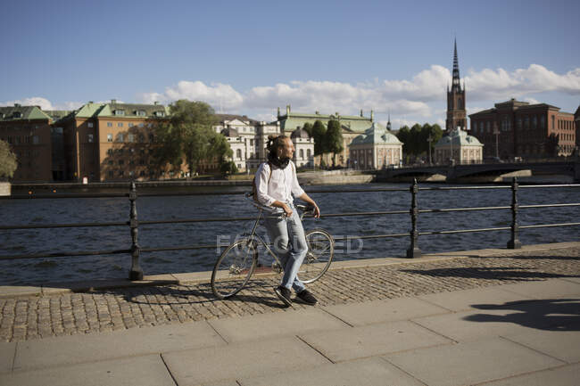 Man leaning on bicycle by harbour — Stock Photo