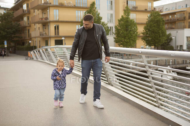 Uomo che cammina con sua figlia sul ponte — Foto stock