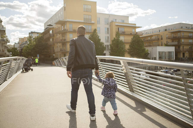 Hombre caminando con su hija en el puente - foto de stock