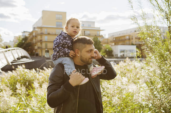 Мужчина катает дочь на спине в парке — стоковое фото