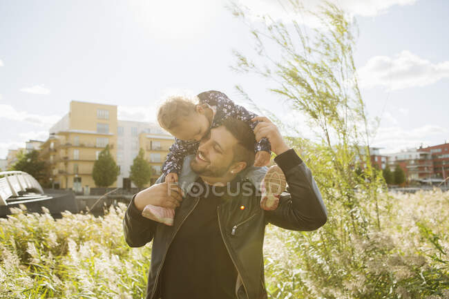 Man giving daughter piggyback ride in park — Stock Photo