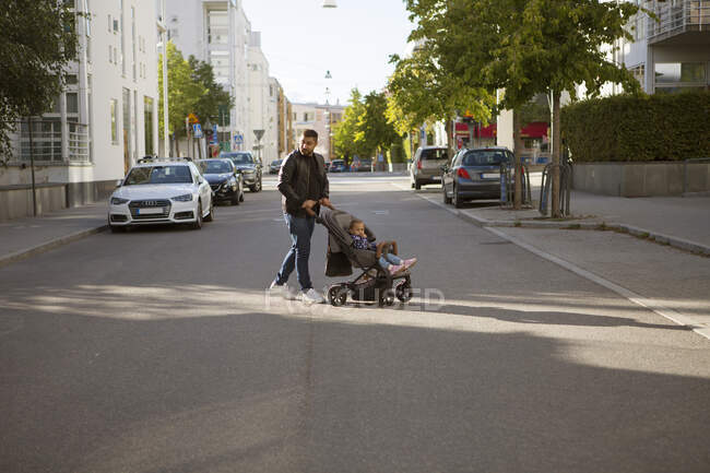 Мужчина толкает свою дочь в коляске — стоковое фото