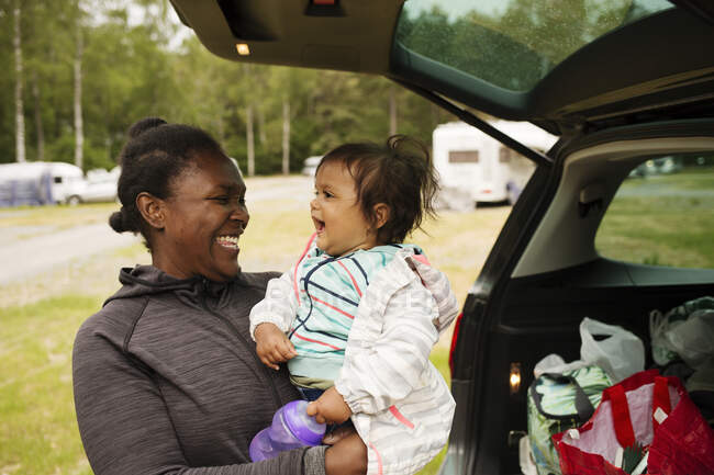 Smiling mother and daughter by car — Stock Photo