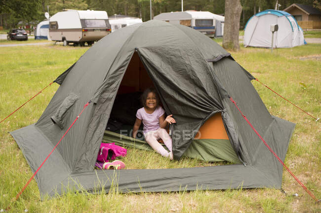 Menina sentada na tenda enquanto acampava — Fotografia de Stock