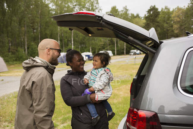 Man and woman with their daughter by car — Stock Photo