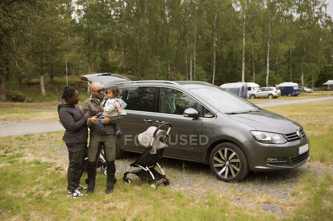 Man and woman with their daughter by car — Stock Photo