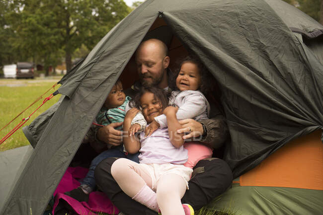 Família abraçando na tenda enquanto acampava — Fotografia de Stock