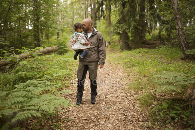 Man holding his daughter while hiking in forest — Stock Photo